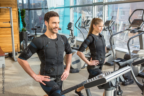 Tableau sur toile Man and woman doing electro muscular stimulation training in a modern gym