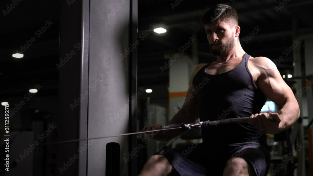 Sports man sitting doing pulldowns, developing upper-back, exhausted workout Sports man sitting doing pulldowns, developing upper-back, exhausted workout