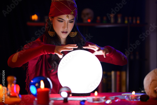 Fortune-teller woman is predicting with a shining crystal ball photo