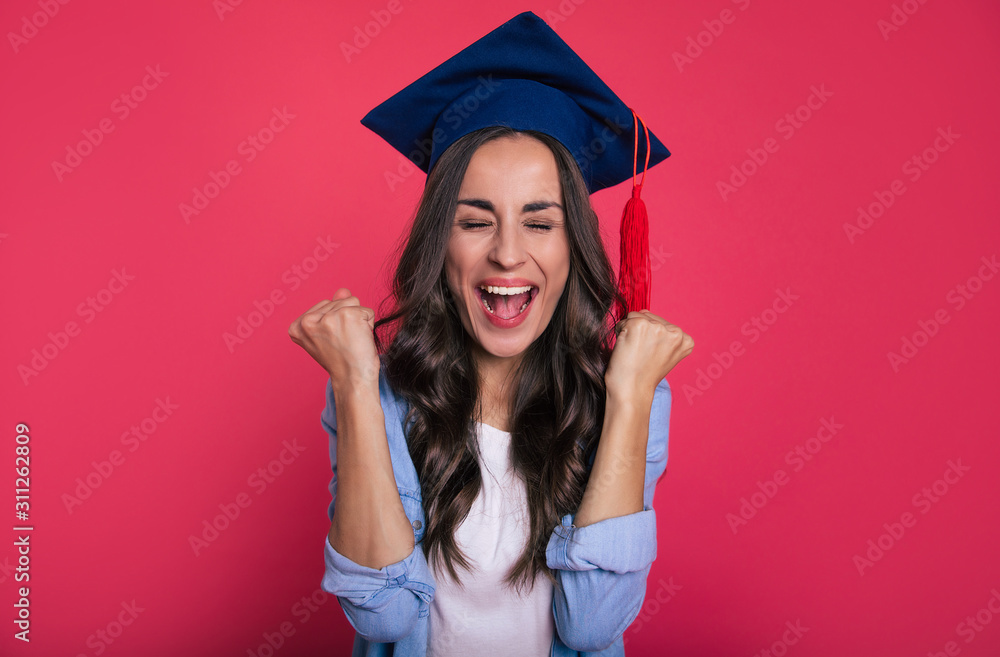 Graduation day! Close-up photo of a wonderful excited student in a casual outfit and a square academic hat, who is extremely happy and shouts with her eyes closed of joy. Graduation day! Close-up photo of a wonderful excited student in a casual outfit and a square academic hat, who is extremely happy and shouts with her eyes closed of joy.