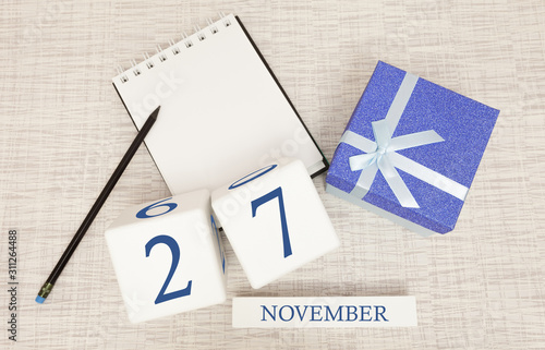 Notepad and wooden calendar for November 27, next to a blue gift box.