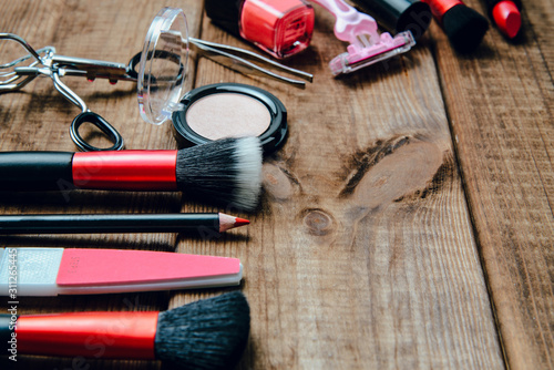 A set of cosmetics on a wooden table. The concept of doing makeup, caring for the appearance of women. Applying brushes, eye shadows, powder.