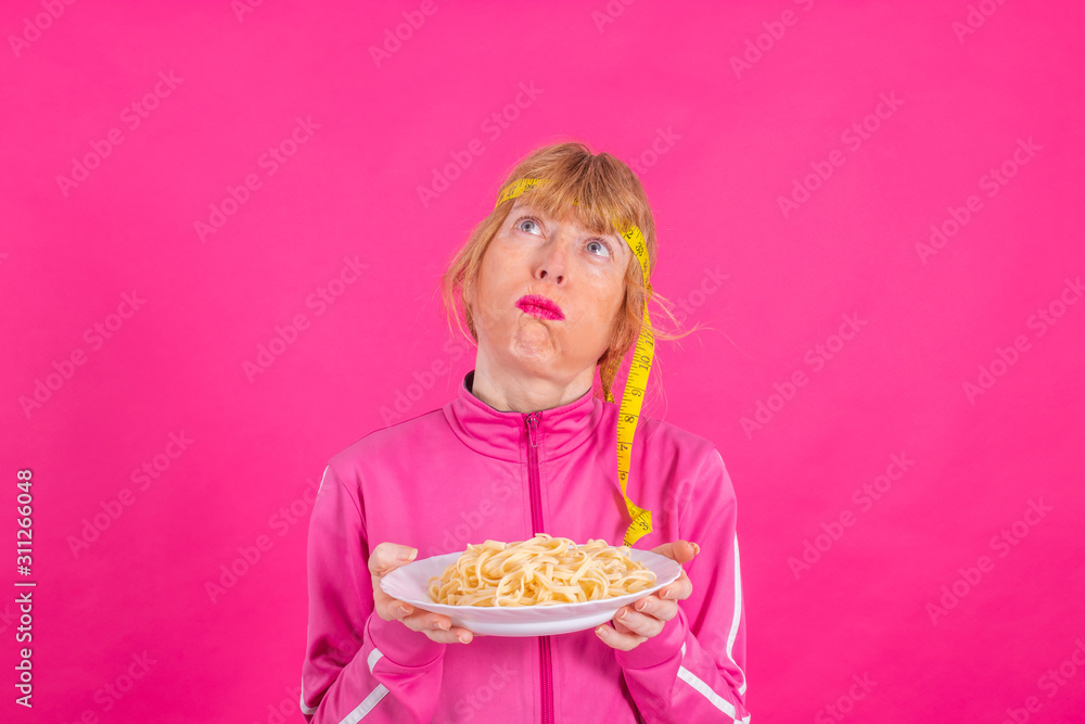 adult woman with sportswear and pasta dish with measuring tape in color background adult woman with sportswear and pasta dish with measuring tape in color background