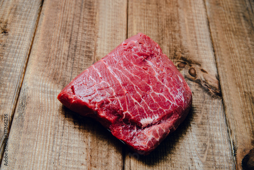 Raw beef, beef steak on wooden countertop, background. The concept of preparing a meal and eating. Fresh red beef, preparing a steak, using meat with a meal.