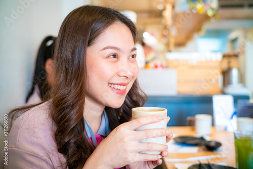 Beautiful asian women hold hot matcha genmai tea drink