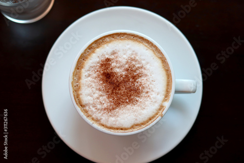 Cappuccino or latte with frothy foam, coffee cup top view closeup.