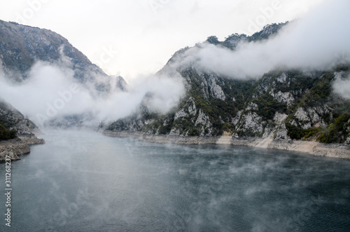 Foggy lake surrounded by mountains in the morning. Peaceful nature in autumn. Lake Piva, Pivsko jezero, Montenegro.Foggy morning in Piva Canyon. River Piva surrounded by mountains. Peaceful nature   photo