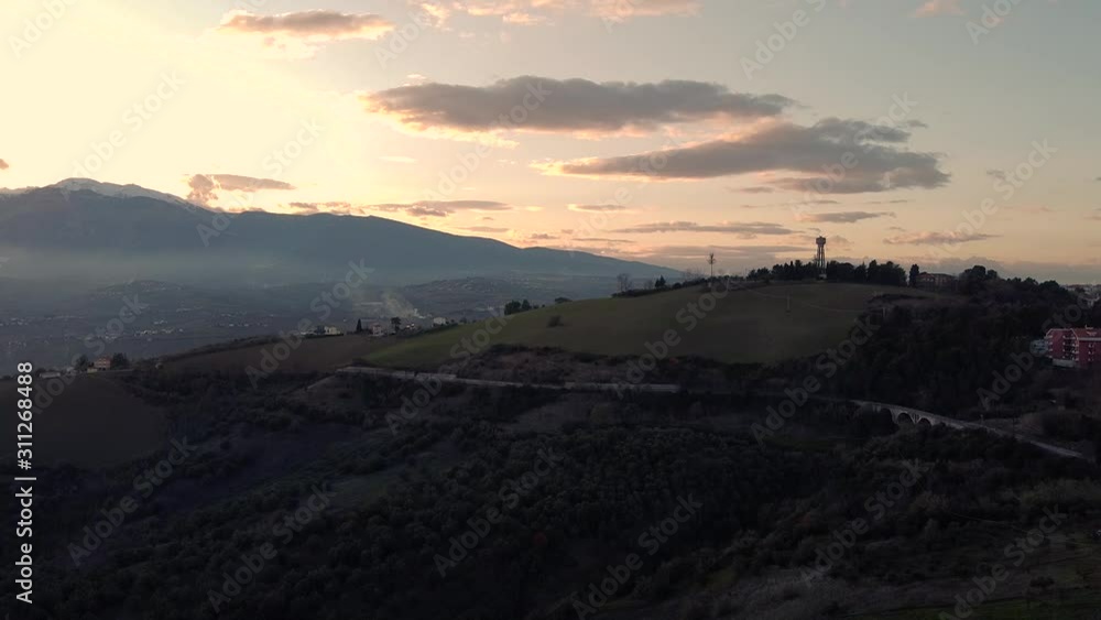 Aerial panorama of hill with water tower at sunset. Mountain in background Aerial panorama of hill with water tower at sunset. Mountain in background