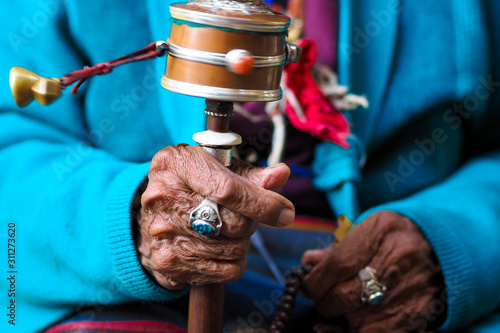 rotation buddhist prayer wheel at old woman's hand, Nepal
