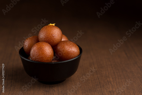 Indian Dessert or Sweet Dish : Gulab Jamun in bowl on wooden background. photo