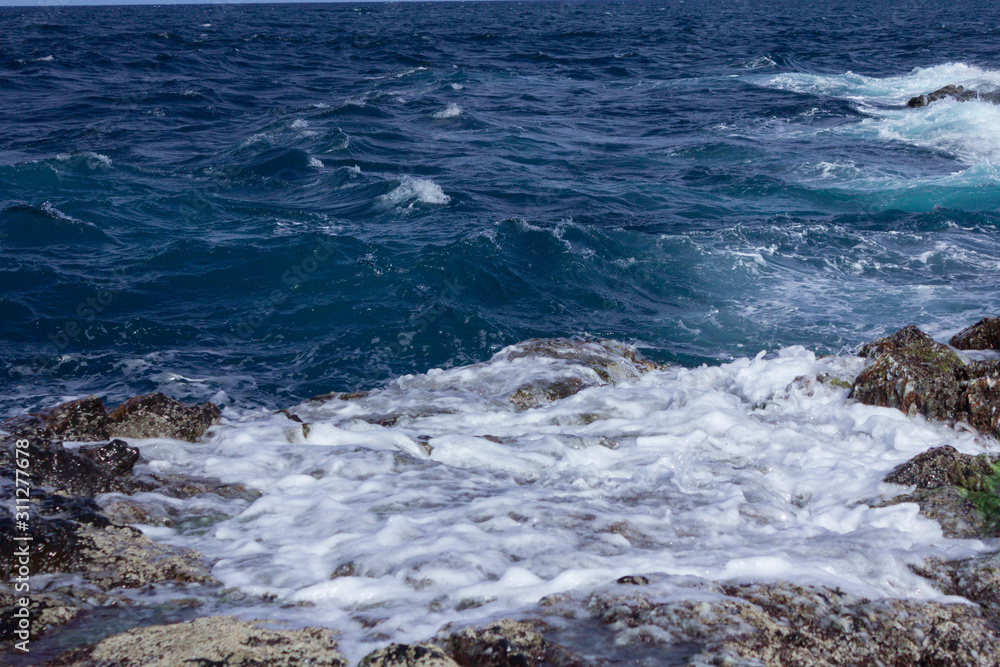 Blue atlantic ocean, white foam and volcanic rock