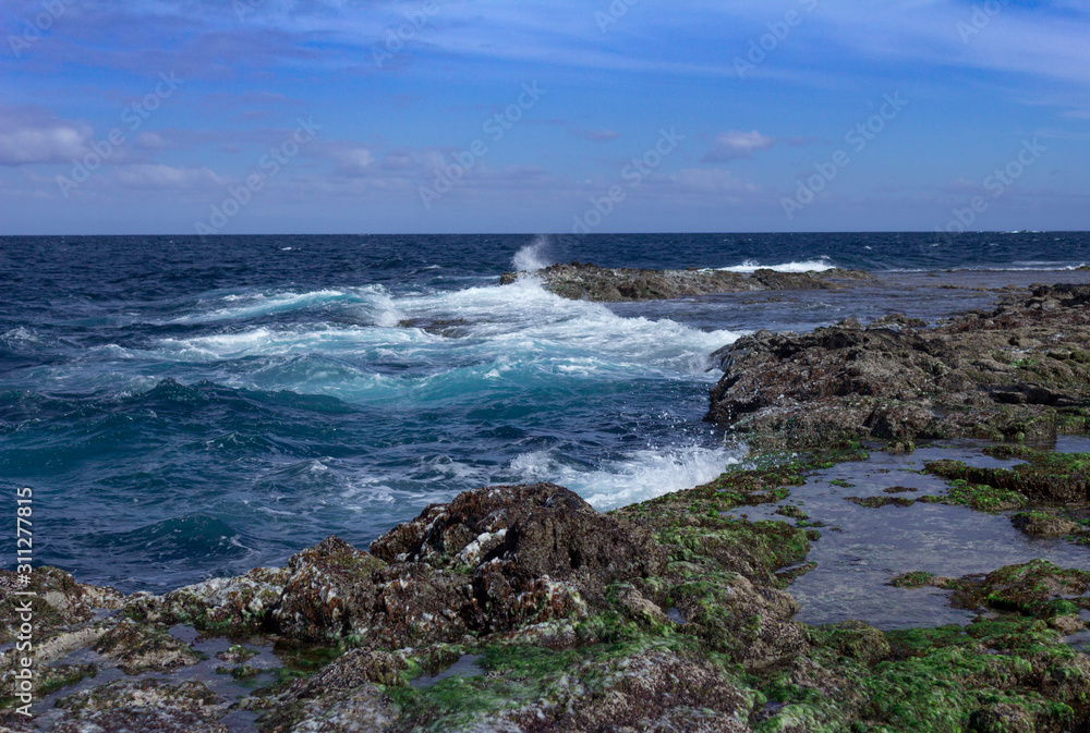 Blue atlantic ocean, white foam and volcanic rock