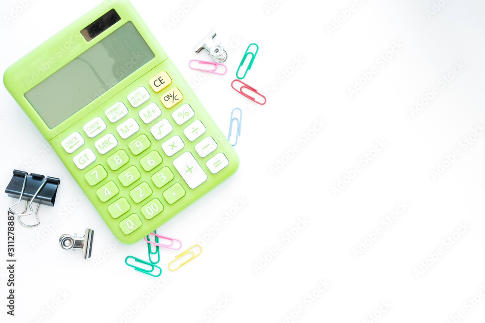 Green calculator and office accessories on white background,with copy space and top view. Green calculator and office accessories on white background,with copy space and top view.