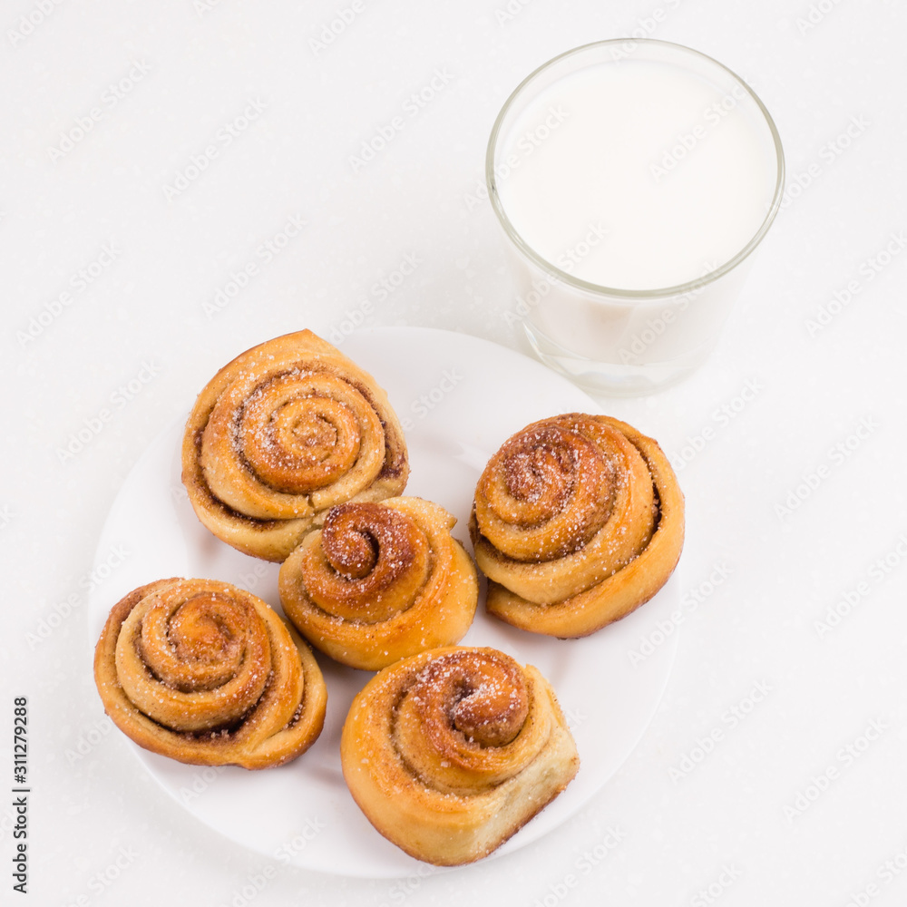 Freshly baked homemade snail buns with sugar and cinnamon with milk in glass. Balanced nutrition, proteins and carbohydrates, cereals Freshly baked homemade snail buns with sugar and cinnamon with milk in glass. Balanced nutrition, proteins and carbohydrates, cereals