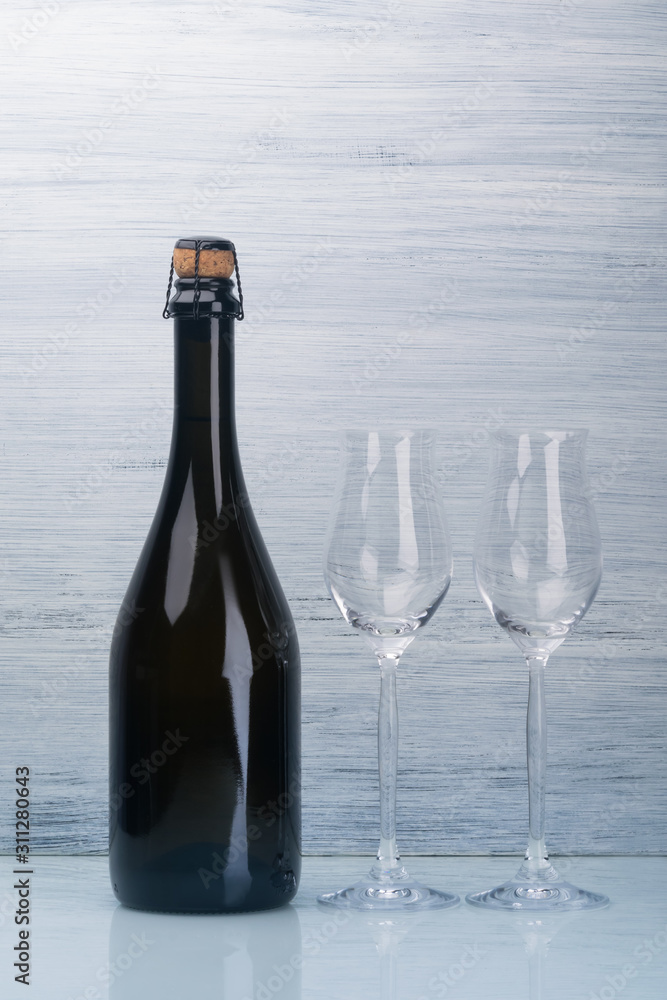 champagne bottle and two empty glasses on a gray background