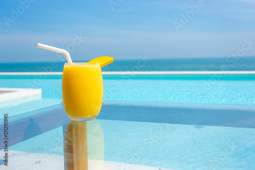 mango smoothies with swimming pool and sea beach background