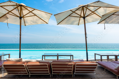 beautiful and empty chair and umbrella with swimming pool and sea beach background