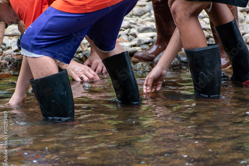 A close up horizontal, landscape orientation shot of students in river boots during a water shed stream study to collect data on the health of the river water.