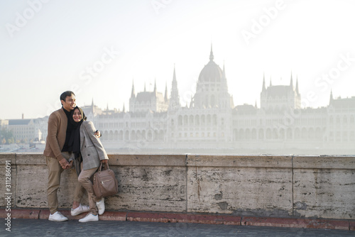 a couple posing against a river background and beautiful city buildings of budapest