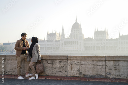 a couple posing against a river background and beautiful city buildings of budapest