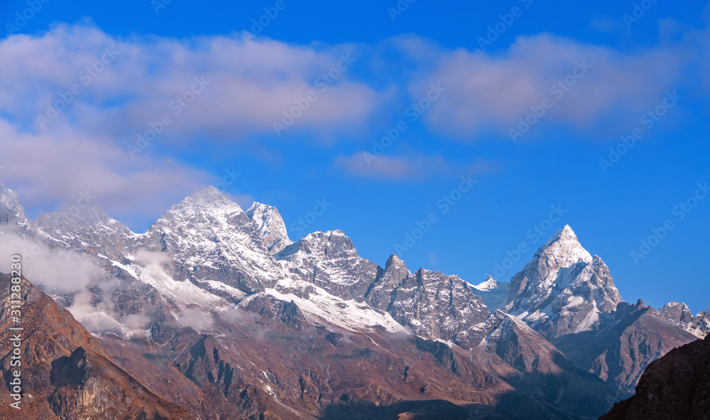 Majestic Himalayan peaks on the background of blue sky with clouds at sunrise