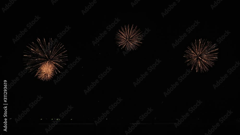 Golden big shiny fireworks with bokeh lights in the night sky. Glowing firework show. New Year's Eve fireworks celebration. Fireworks Festival. Golden big shiny fireworks with bokeh lights in the night sky. Glowing firework show. New Year's Eve fireworks celebration. Fireworks Festival.