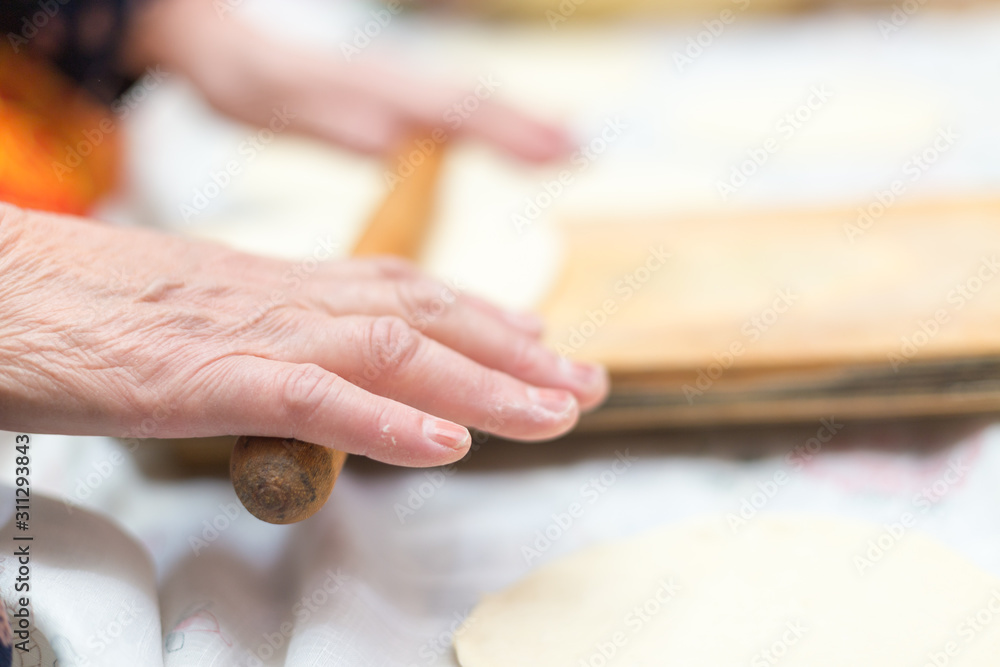 cook, female hand rolls the dough on a wooden board - obrazy, fototapety, plakaty 