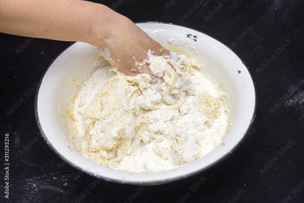 Hands of the cook prepare the dough for bread on a black background. Restrained shot with flour. Hands of the cook prepare the dough for bread on a black background. Restrained shot with flour.