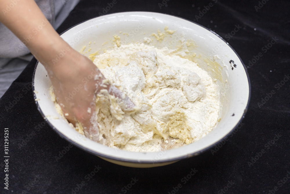 Hands of the cook prepare the dough for bread on a black background. Restrained shot with flour. Hands of the cook prepare the dough for bread on a black background. Restrained shot with flour.