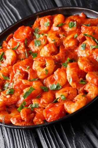 Fried shrimp in tomato sauce close-up in a plate on the table. vertical photo