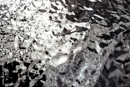 The surface of the water in black and white color with light reflection.