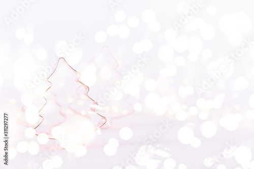 Assorted Christmas Tree Copper cookie cutters on white sparkling background with bokeh lights. Holiday Christmas and New Year background. Horizontal with festive bokeh lights