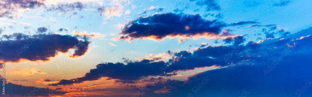 Blue and yellow clouds glow in the sky at sunset.