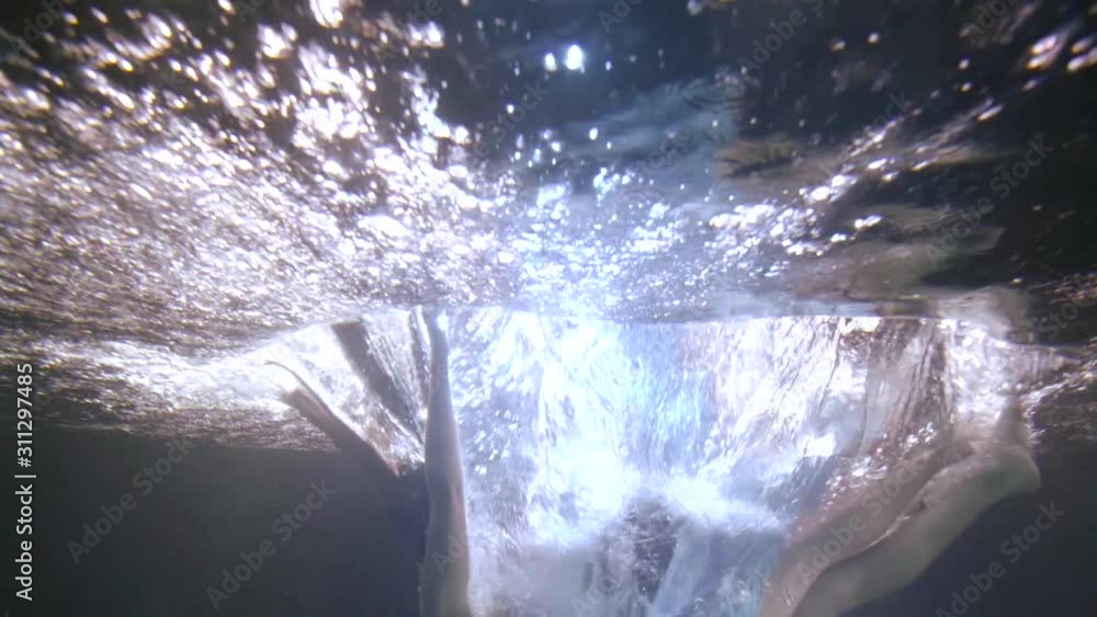 woman is falling inside water of swimming pool, underwater shot