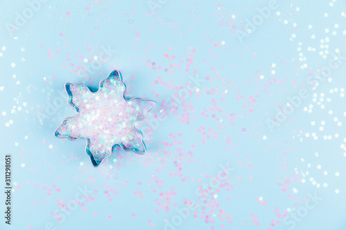 Quadro su tela Flatlay with snowflake cookie cutter and snowflake sprinkles on blue background