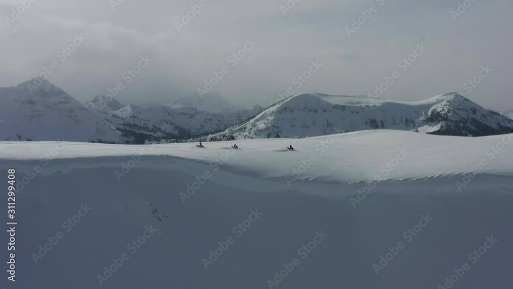 A group of snowmobiles on a snowy mountain ridge in Montana drone. A group of snowmobiles on a snowy mountain ridge in Montana drone.