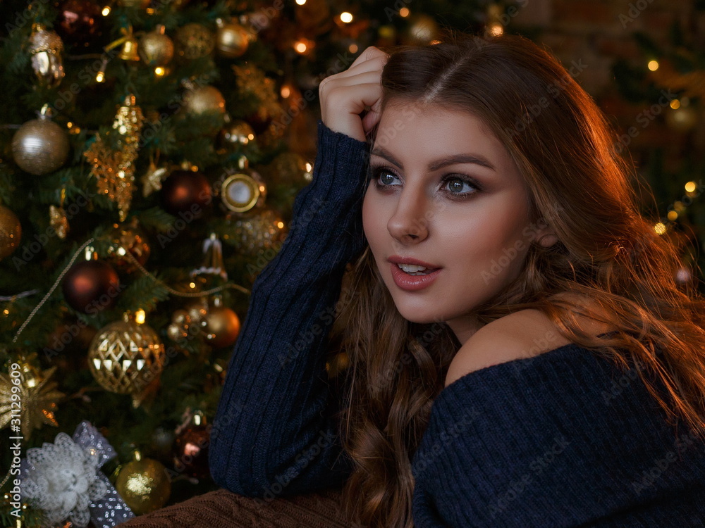 Young beautiful girl with loose hair close up sitting at the Christmas tree with Christmas toys Young beautiful girl with loose hair close up sitting at the Christmas tree with Christmas toys