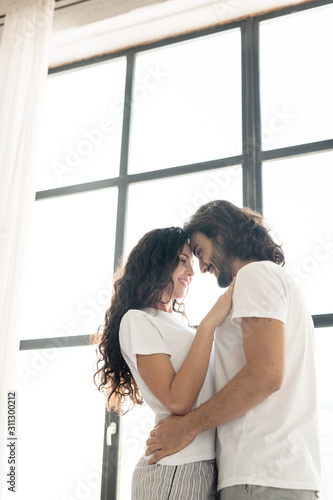 Young affectionate smiling couple in white t-shirts standing close to each other