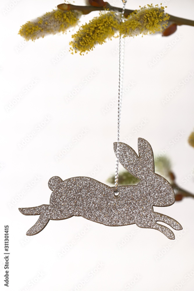 Obraz premium Easter time. Easter rabbit silver on willow twigs on a white background. Easter concept. Spring religious holiday background.