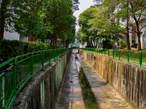 Fototapeta Naklejka Na Ścianę i Meble -  Tree lined water canal channel in a residential housing estate in Singapore
