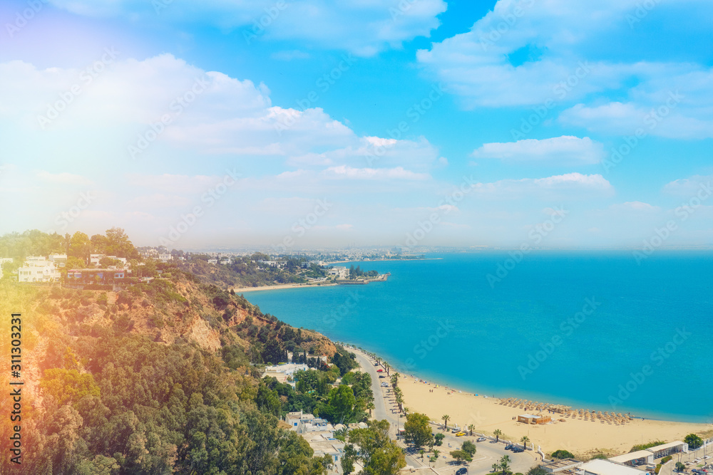 Top view of the beach, sea and coastal road to the city in Sidi Bou Said, Wallpaper background. Mediterranean seascape, Tunisia. June 2019