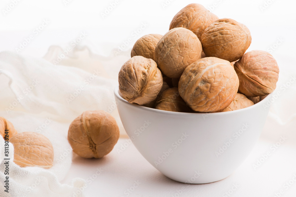 Walnuts in a white ceramic bowl on a white background Walnuts in a white ceramic bowl on a white background