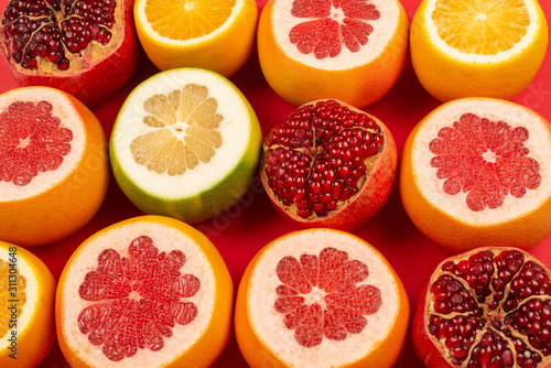 Fototapeta Naklejka Na Ścianę i Meble -  Grapefruit, orange, pomegranate, citrus sweetie on red background.