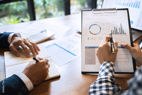 Foto Two business teamwork calculating a valuation in workplace.