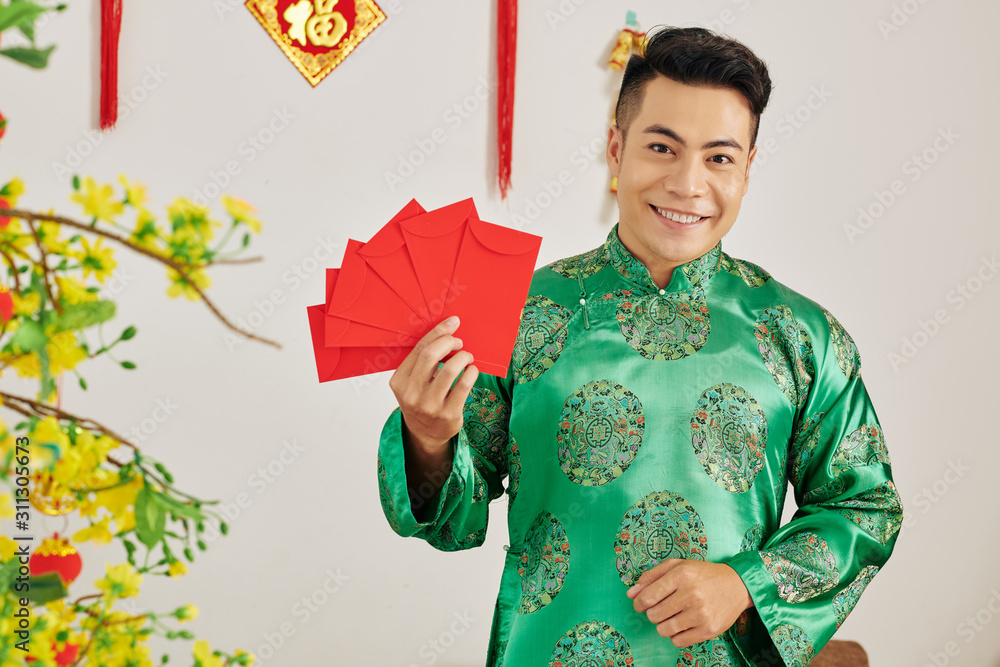 Attractive young Asian man holding red envelopes as traditional presents for Chinese New Year Attractive young Asian man holding red envelopes as traditional presents for Chinese New Year