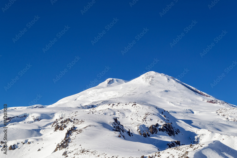 Two snow-white peaks of the mountain Elbrus against a clear cloudless blue sky 