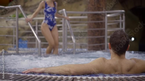 romantic date of adult lovers in termal pool pool, woman is lowering in water photo