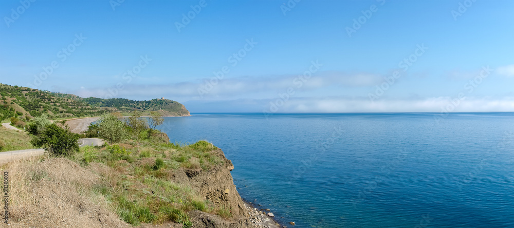 Low clouds above the sea and hilly seashore, panoramic view