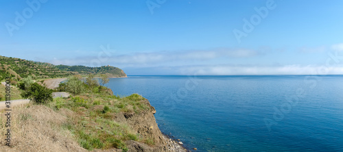 Low clouds above the sea and hilly seashore, panoramic view