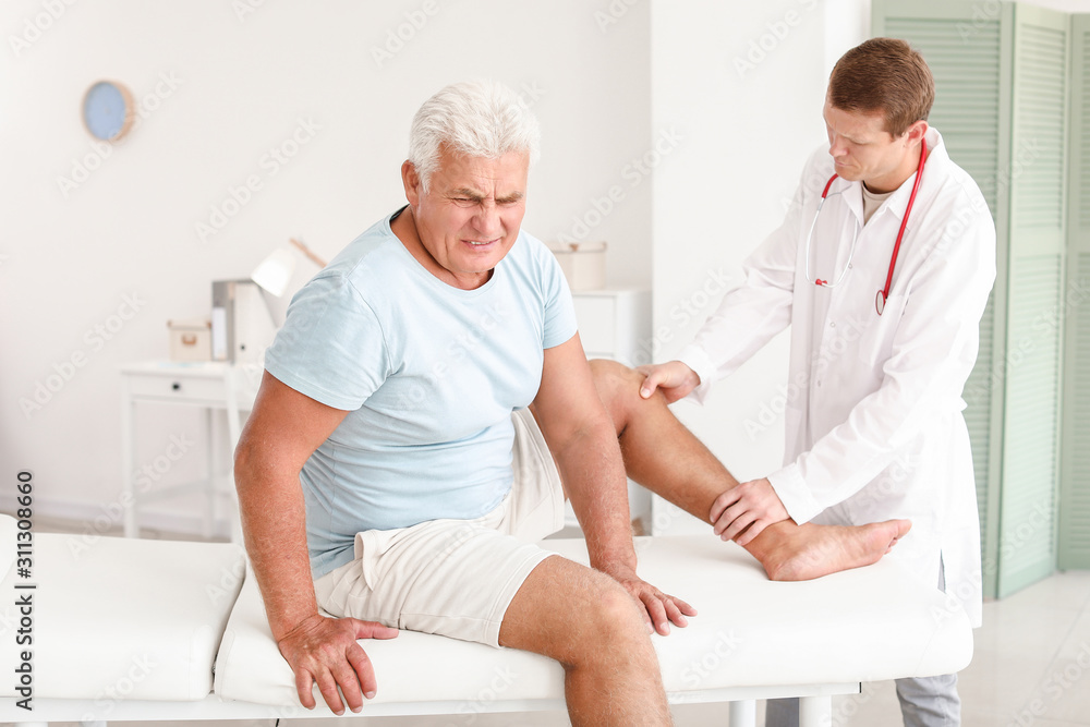 Fototapeta premium Doctor examining mature man with joint pain in clinic